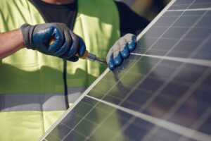 A professional solar installer using a tool to secure solar panels during a solar installation, ensuring a durable and efficient solar system.