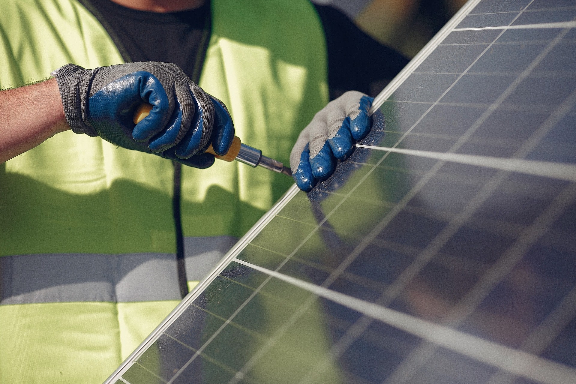 A professional solar installer using a tool to secure solar panels during a solar installation, ensuring a durable and efficient solar system.